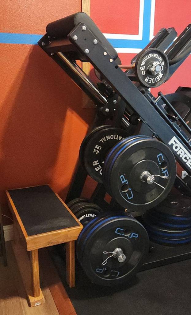 wood bench beside a leg press