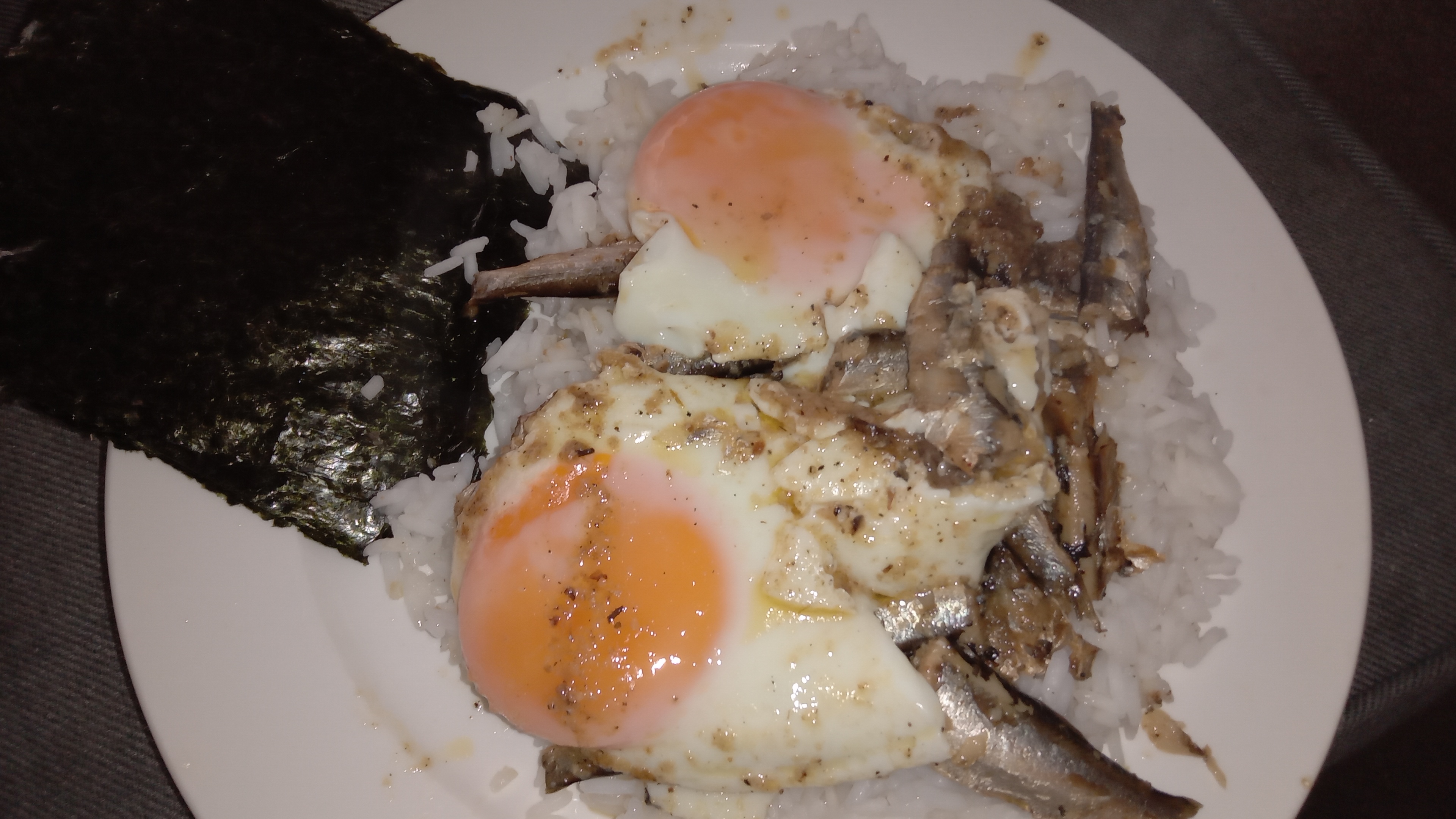plate of rice, fried eggs and sardines, wish pieces of Nori sheets on the side