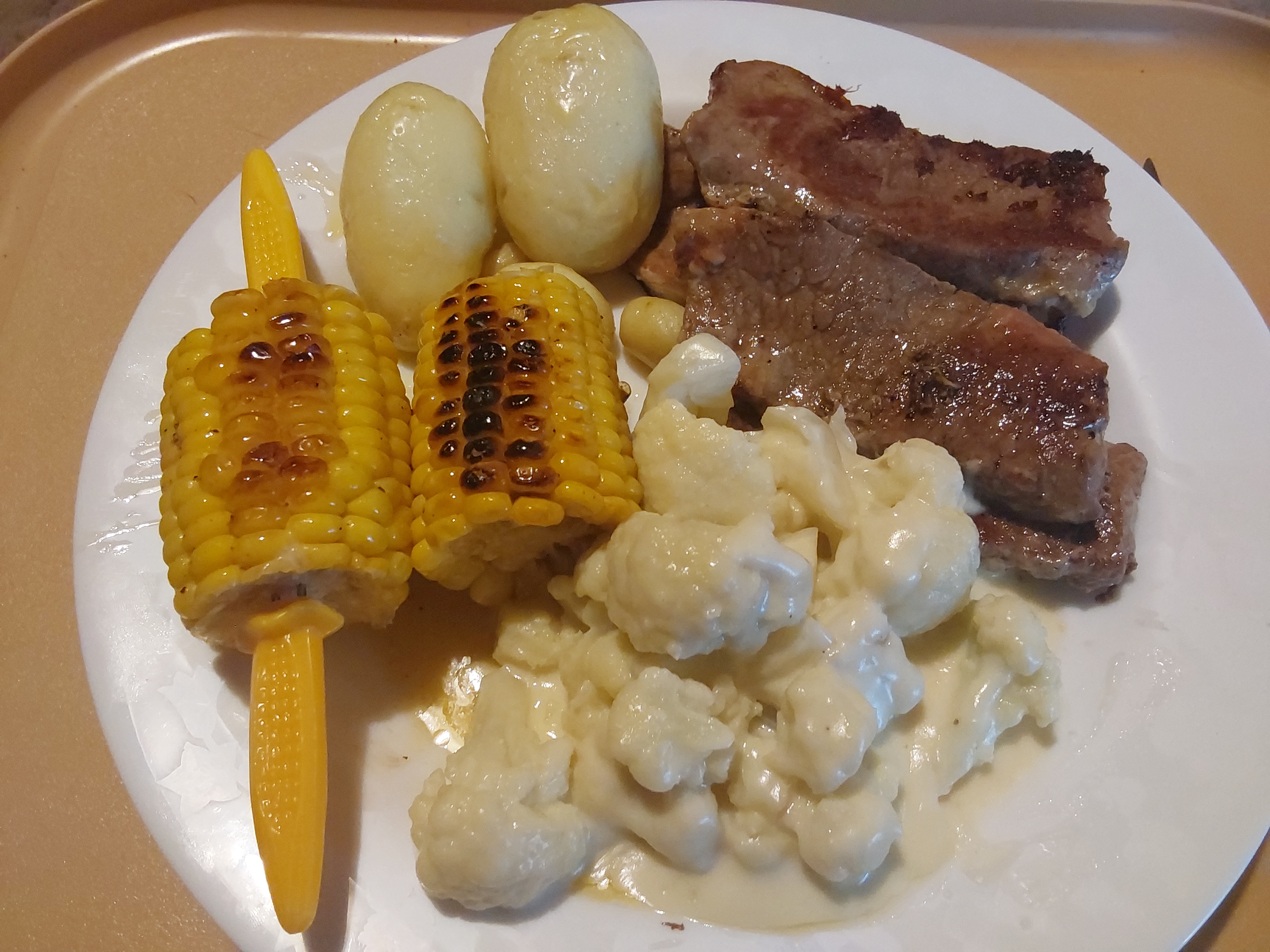plate of steak, potatoes, corn and cauliflower in cheese sauce