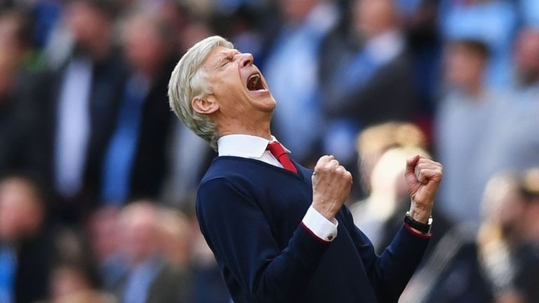 Photo of Arsene Wenger celebrating with double clenched fists. He is wearing a white shirt, red tie and navy blue jersey. He is leaning back, screaming with his eyes closed.