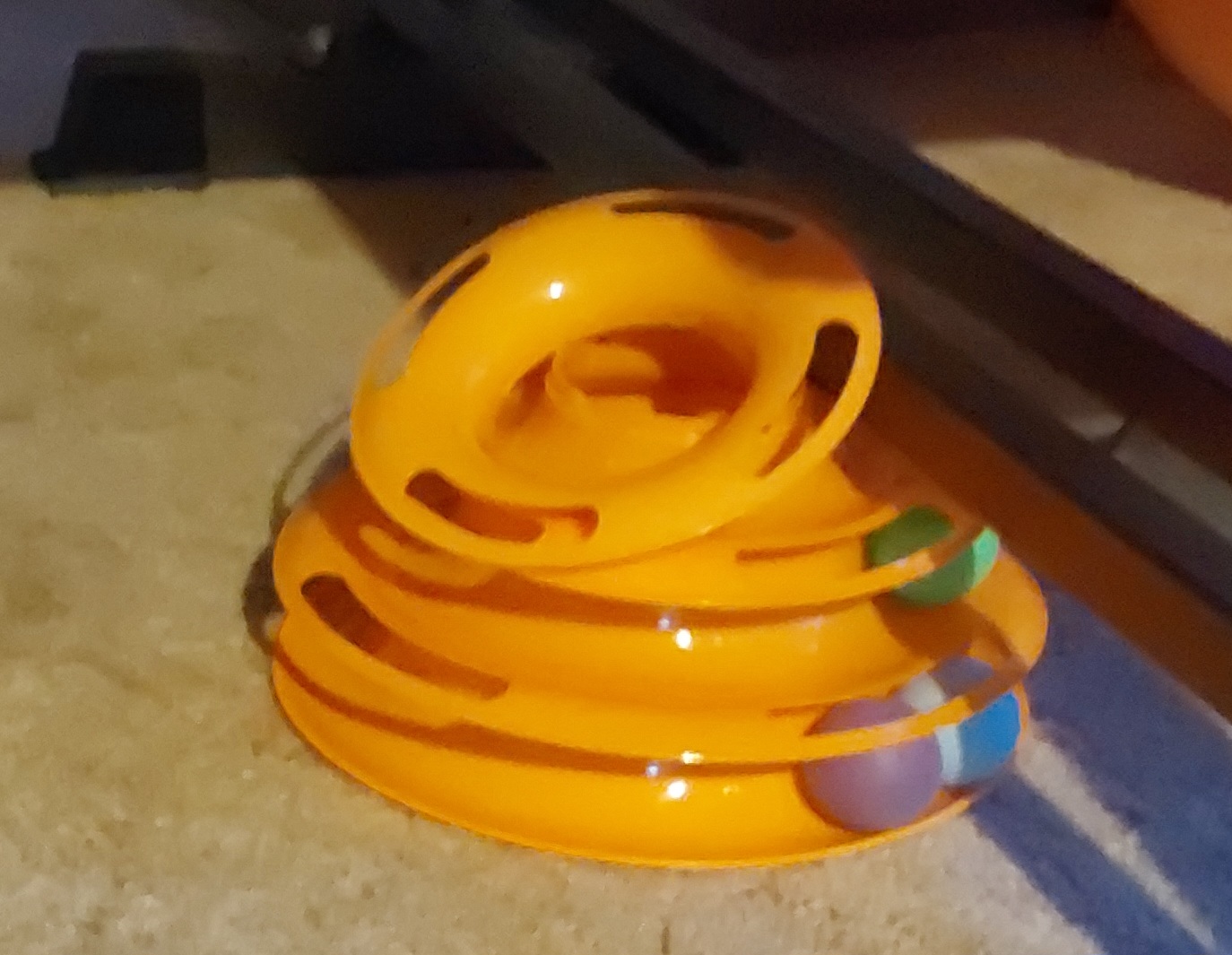 Image of cat toy with three rings holding balls in a channel.  The top ring has been pulled off allowing the ball to be removed