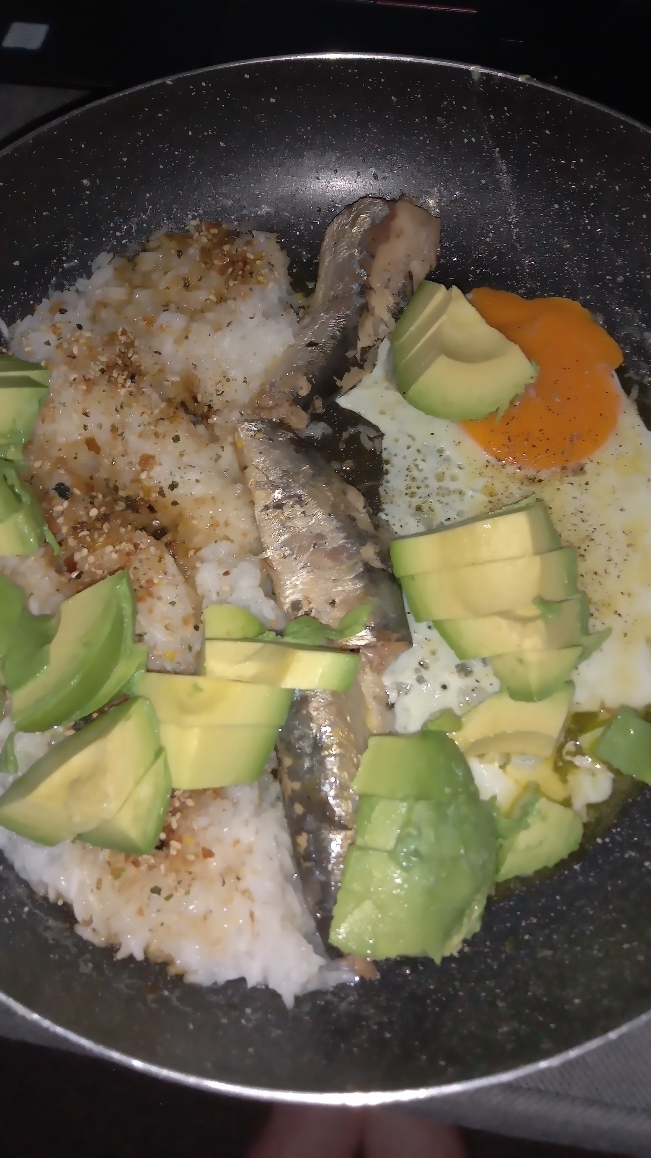 pan with seasoned rice avocado sardines and fried egg