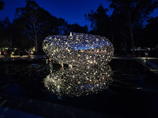 A photo of a sculpture at night, lit up with light shining through holes in the work