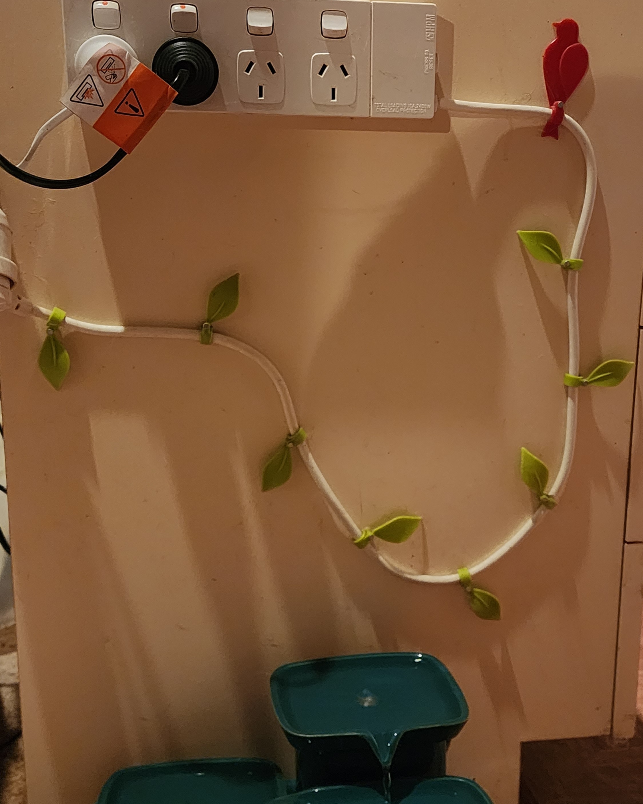 an extention cord lead secured with cable clips decorated with leaves and a bird to make it look like a vine
