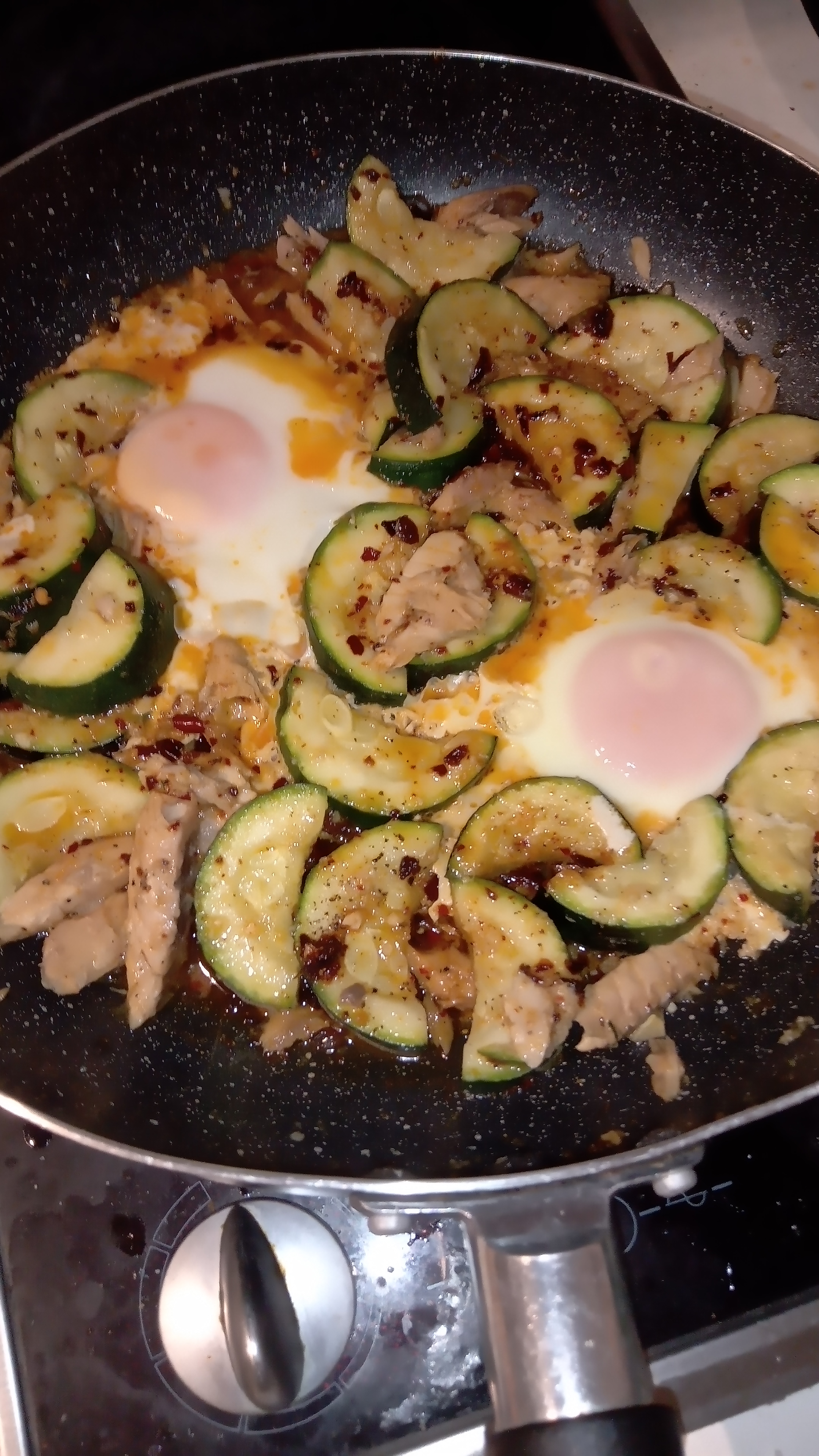 saucepan with a finished meal of zucchini and mackerel sauteed with butter garlic and chilli, and finished with fried eggs