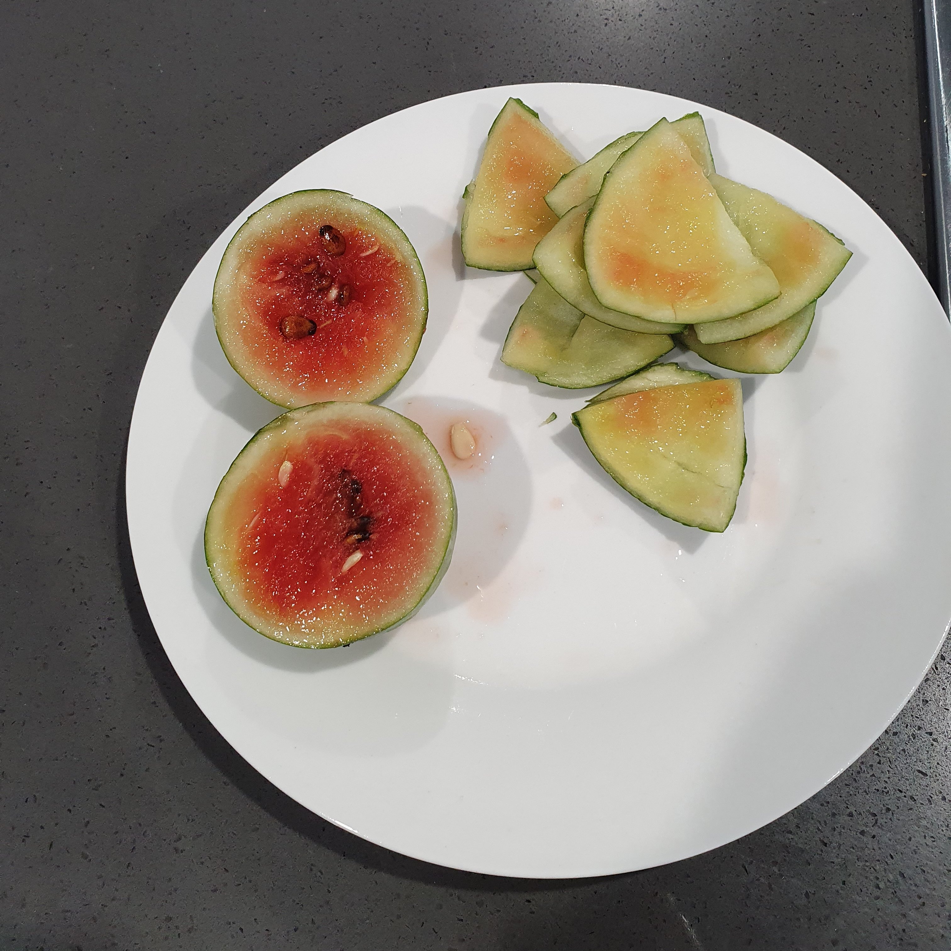 Photo of a really small watermelon that has been cut in half, showing inside is red and ripe