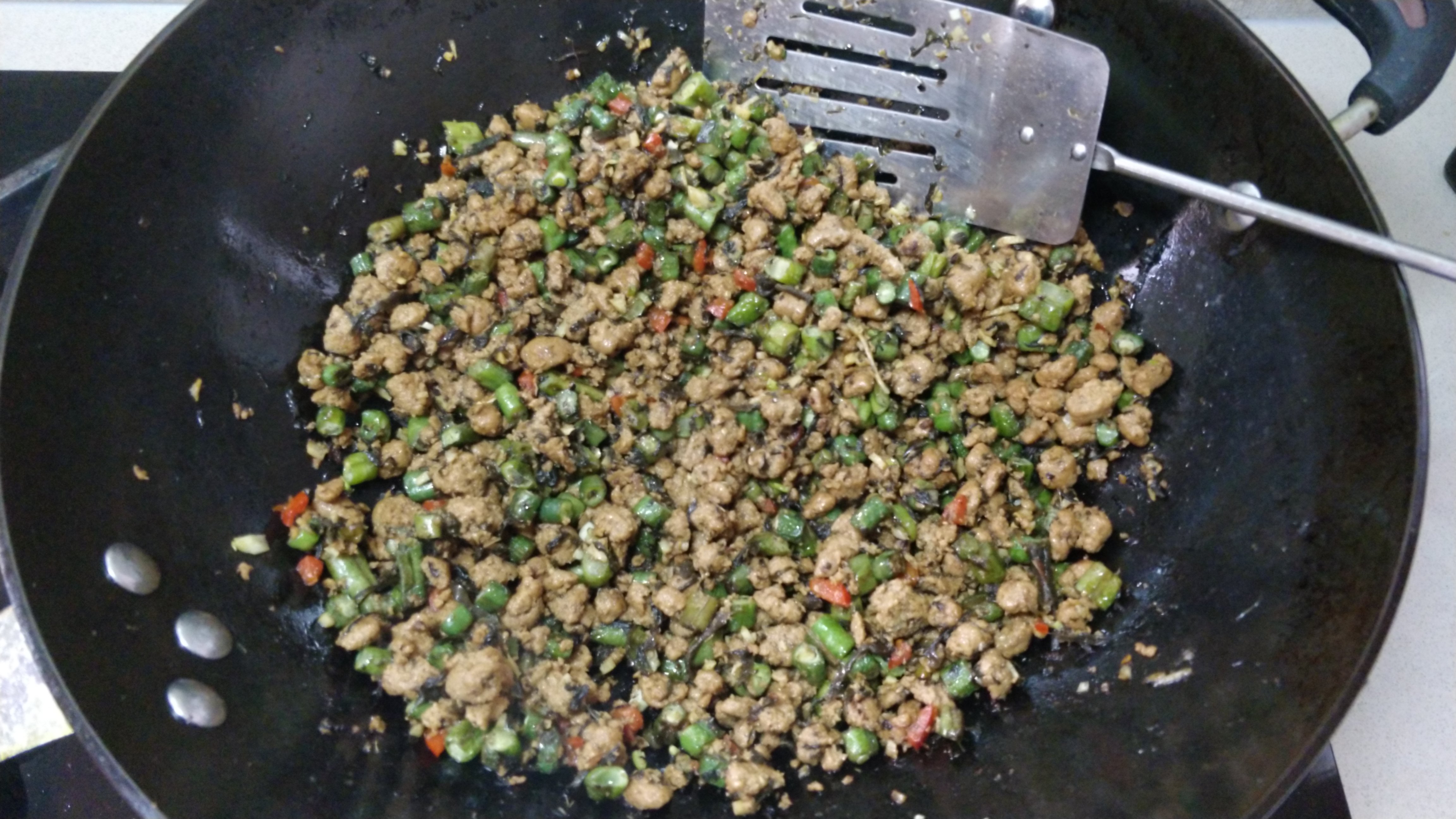 long beans cut in small sections stir fried with ginger, garlic, chilli and a fair whack of marinated vegan mince, glistening in a large wok