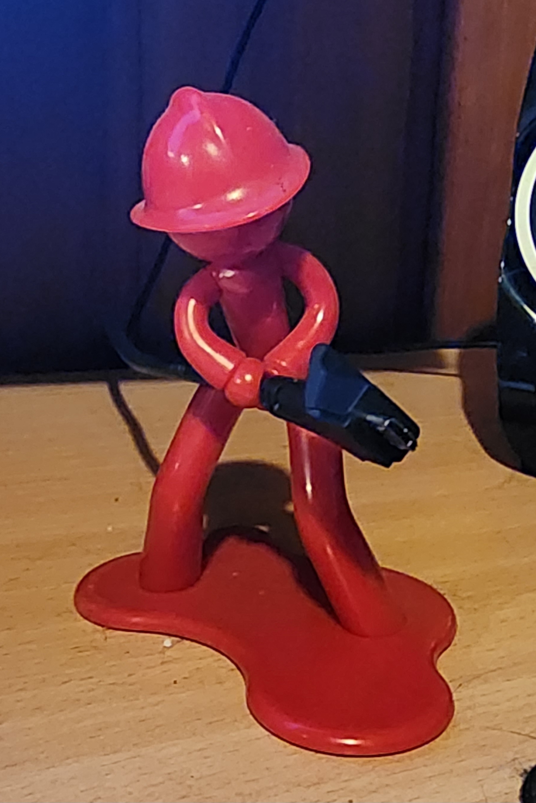 Red plastic fireman figure holding a charging cord like a fire hose