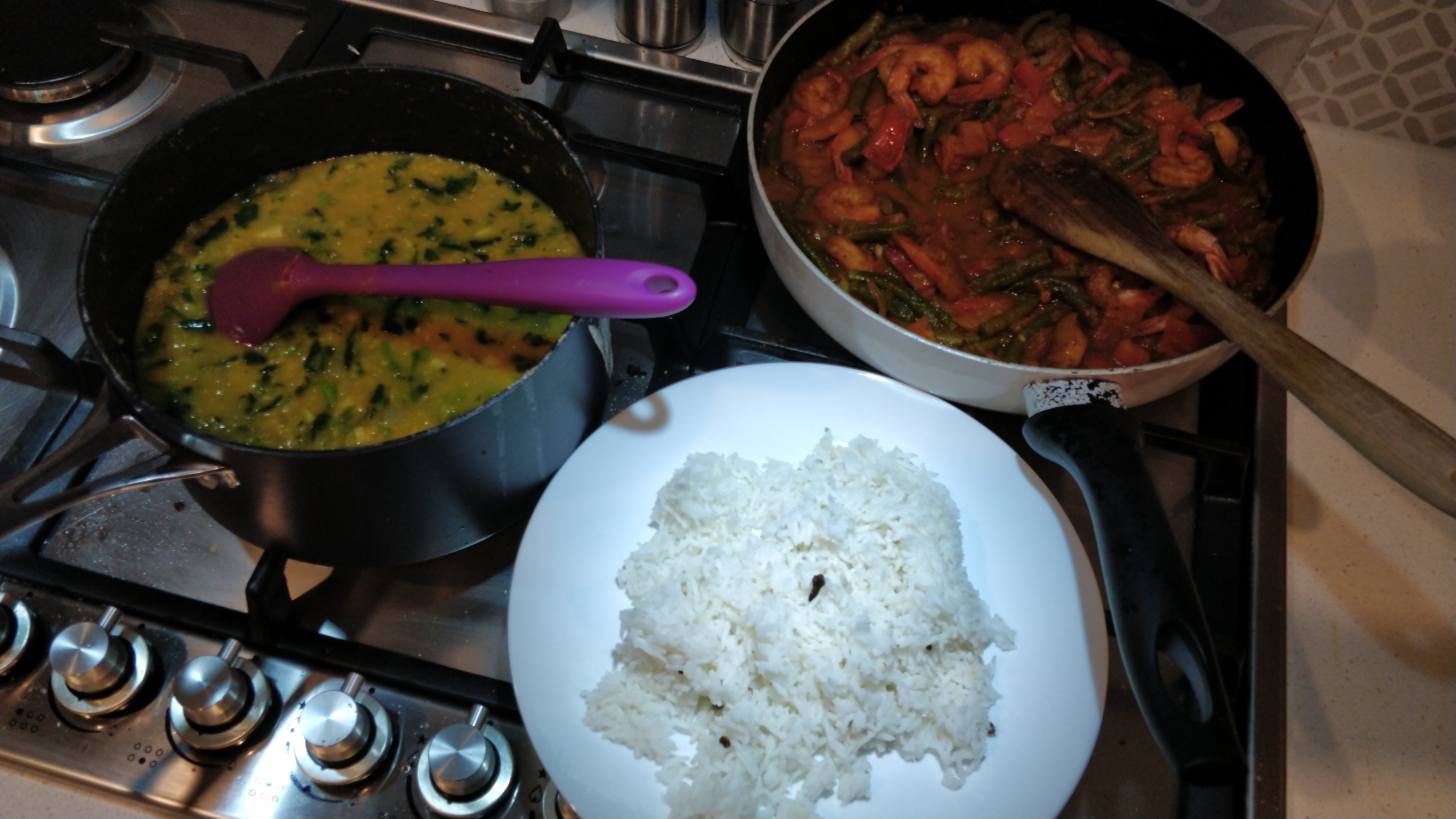 two pots of curry and a plate of rice on a stove