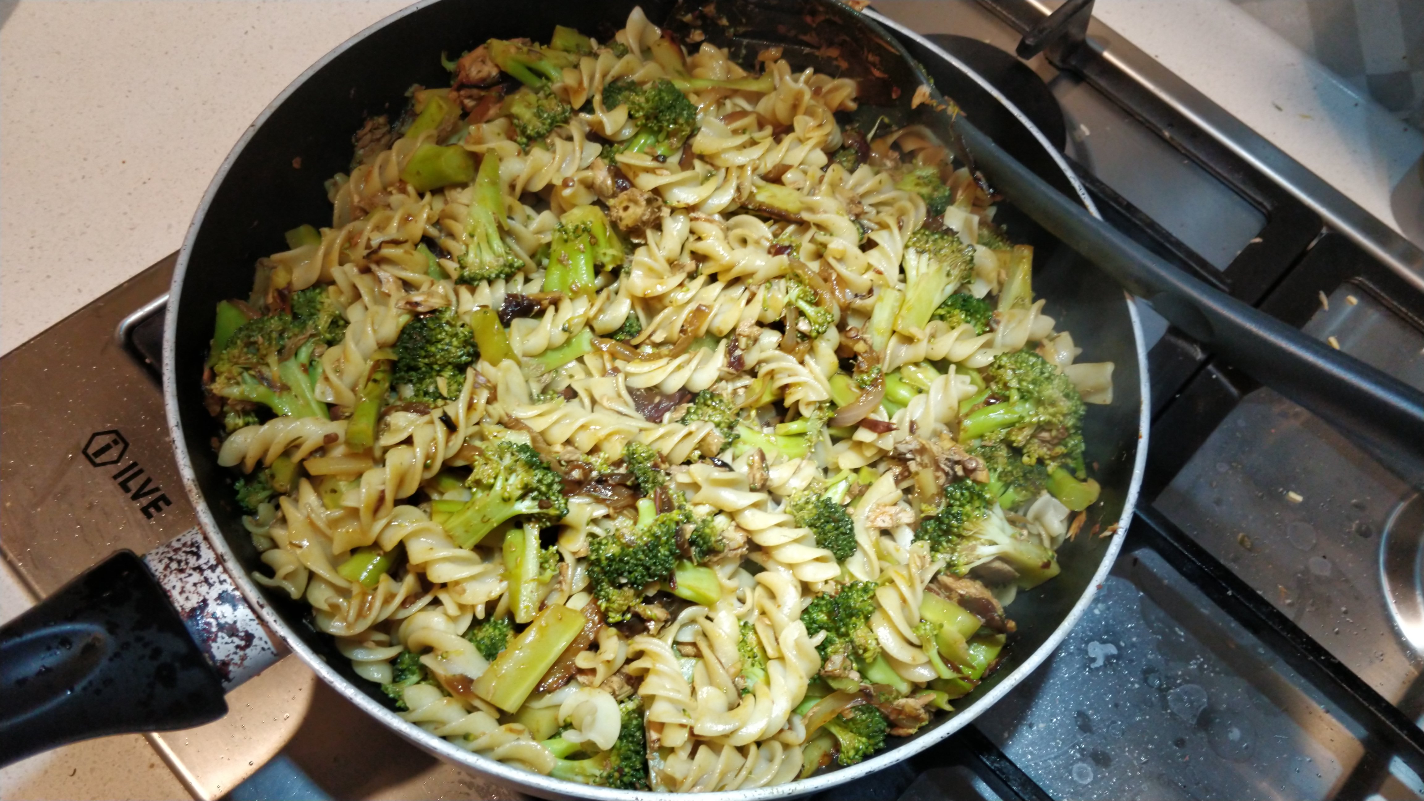 pasta with broccoli and tuna and some red chipotle in adobo sauce stirred through, in a pan on the stove